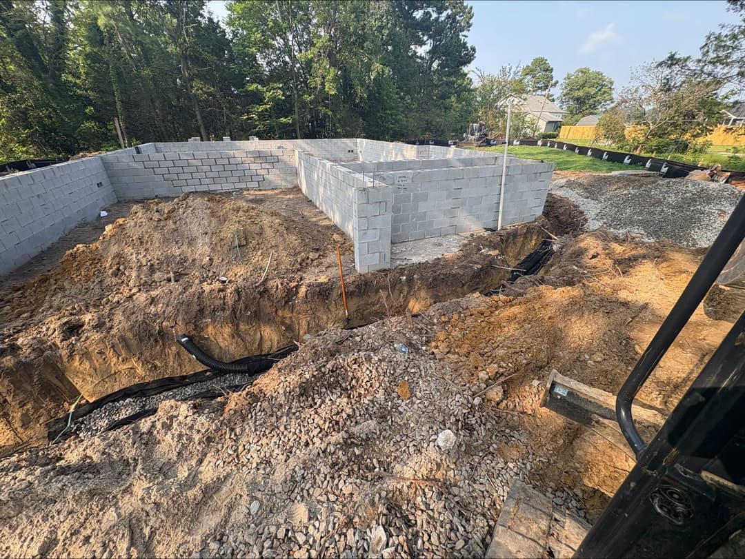 Construction site with cinder block foundation and excavated area for building.
